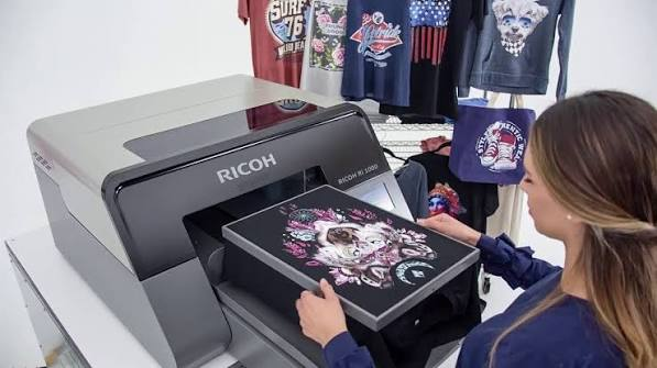 Impresora directa aplicando un diseño a color sobre una prenda